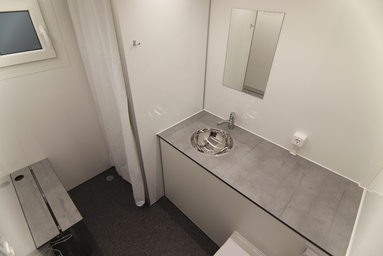 Douche en wastafel binnenin de mobiele badkamer